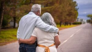 Older couple walking arm in arm down a road